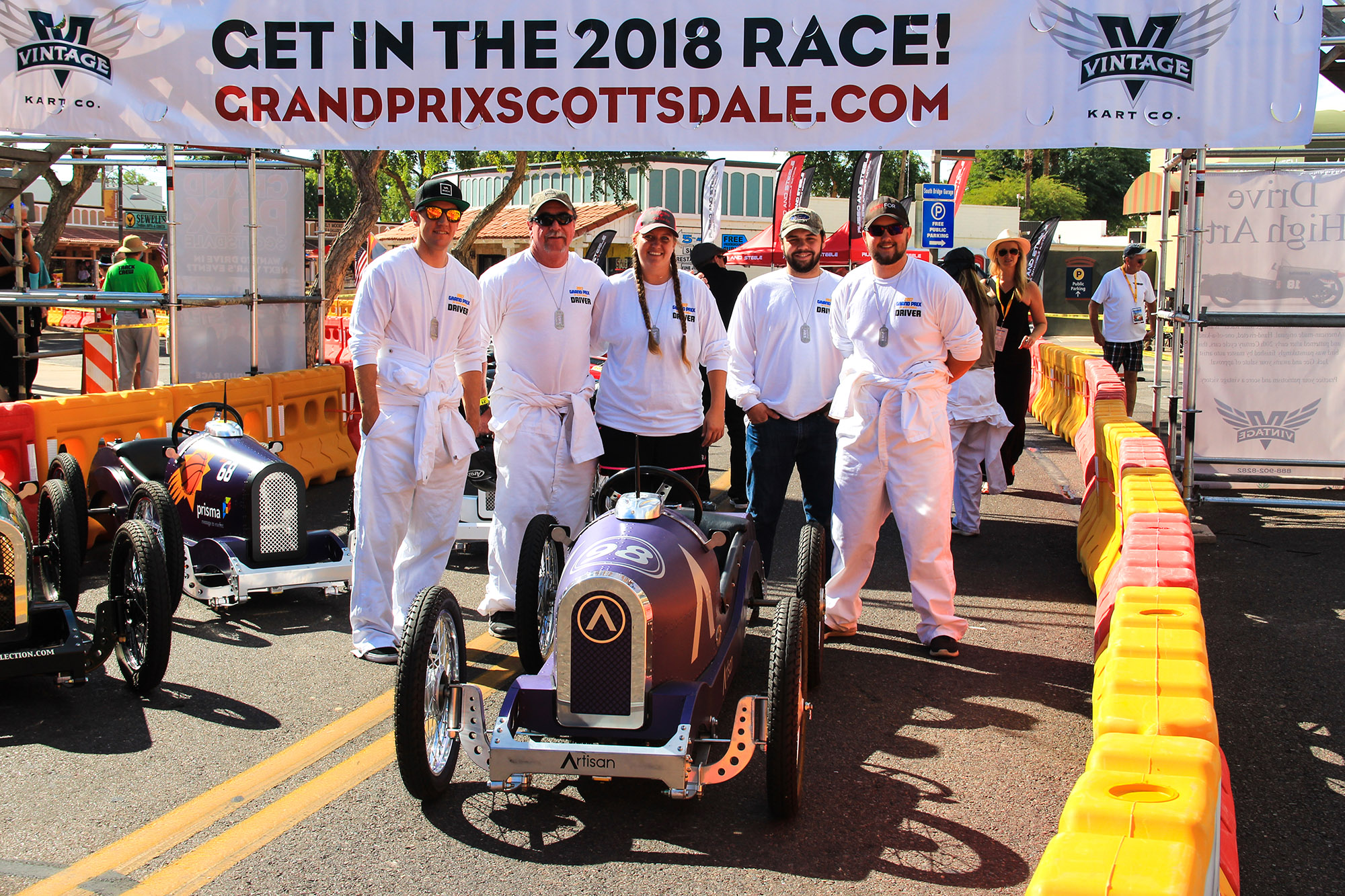 Artisan Colour team members in racing suits at the 2017 Grand Prix of Scottsdale, highlighting their sponsorship and participation in the vintage kart race.